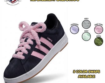 May include: A dark navy sneaker with pink stripes and thick, fluffy baby pink laces tied in a bow. The text reads FLUFFY REPLACEMENT LACE SWAPS and 5 COLOR SWAPS AVAILABLE. Five circular swatches show grey, lavender, baby pink, mint, and moss colors.