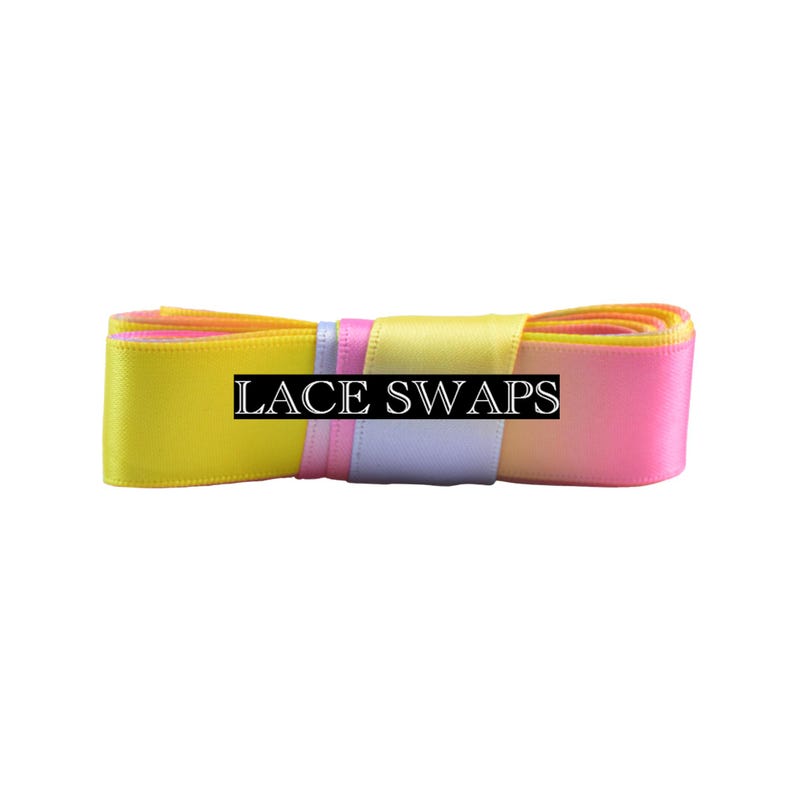 May include: A coiled length of satin ribbon featuring a gradient of bright yellow, soft lavender, and vibrant pink colors. The ribbon is secured with a central band that displays the text LACE SWAPS in a bold, white, serif font on a black background.