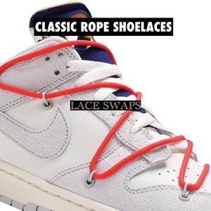 Peut inclure: Gros plan d'une basket blanche et grise avec des lacets en corde rouge. Les lacets sont enfilés dans les œillets en croix. Le texte "CLASSIC ROPE SHOELACES" et "LACE SWAPS" est affiché dans l'image.