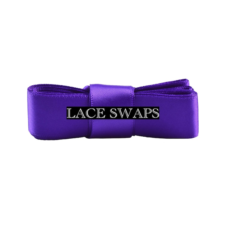 May include: A vibrant purple satin ribbon folded into a compact rectangular shape, featuring a smooth, reflective texture. The text LACE SWAPS is printed in a clear, white serif font across the center of the ribbon, which is secured by a matching purple band.