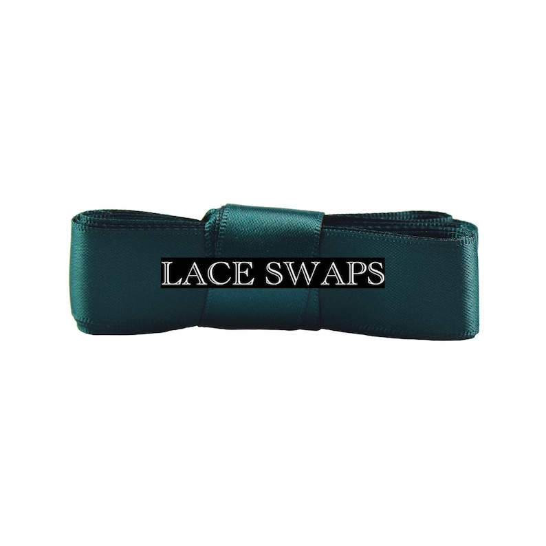 May include: A dark emerald green satin ribbon folded into a rectangular shape with a central band. The text LACE SWAPS is printed in white capital letters across the center of the ribbon, which features a smooth, reflective fabric texture.