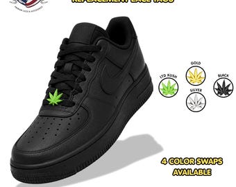 May include: A black sneaker featuring a green marijuana leaf metal lace tag on the laces. The image displays text reading MARIJUANA LEAF METAL REPLACEMENT LACE TAGS and 4 COLOR SWAPS AVAILABLE, with circular icons showing gold, silver, black, and green leaf options.