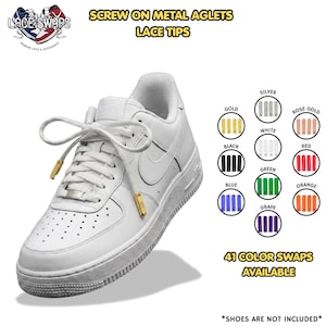 Könnte beinhalten: Ein weißer Sneaker mit goldenen, zum Aufschrauben gedachten Metall-Schnürsenkelenden. Das Bild zeigt den Text "SCREW ON METAL AGLETS LACE TIPS" und "41 COLOR SWAPS AVAILABLE" sowie eine Farbkarte mit Gold, Silber, Roségold, Weiß, Schwarz, Rot, Blau, Grün, Orange und Lila.