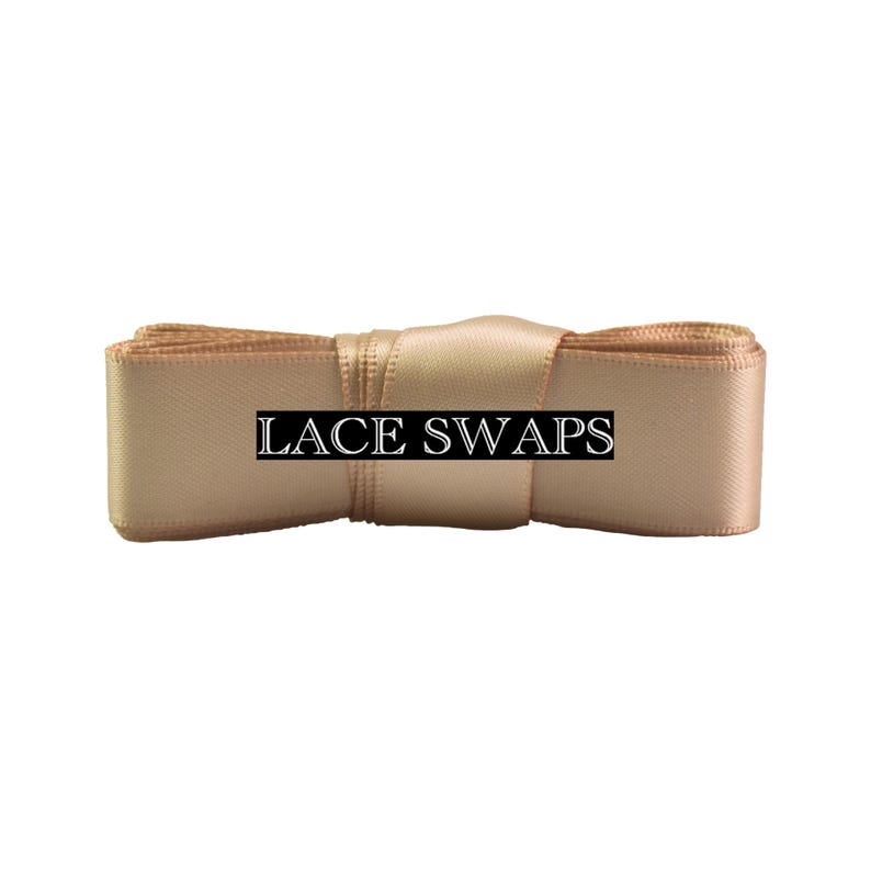 May include: A roll of champagne-colored satin ribbon featuring a smooth, reflective texture. A black rectangular label with the white text LACE SWAPS is centered horizontally across the front of the ribbon, which is coiled into a flat bundle.