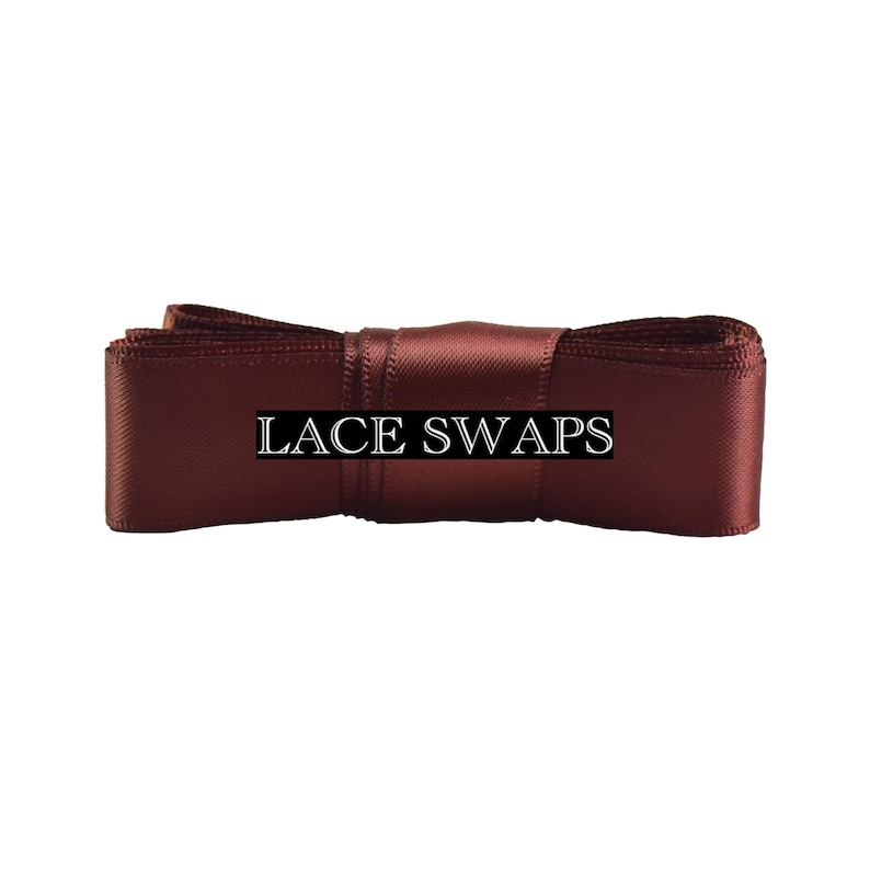 May include: A dark burgundy satin ribbon folded into a rectangular shape with a smooth, reflective finish. The text LACE SWAPS is printed in white capital letters across the center of the ribbon, which is secured by a central band of fabric.