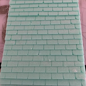 May include: A close-up of a light green foam sheet with a textured pattern that resembles shingles. The foam sheet is used for model making and crafting.