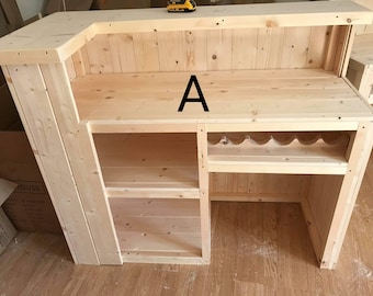 May include: A wooden bar counter with a shelf and a wine rack. The counter is made of unfinished wood and has a simple design. The letter "A" is written on the counter.