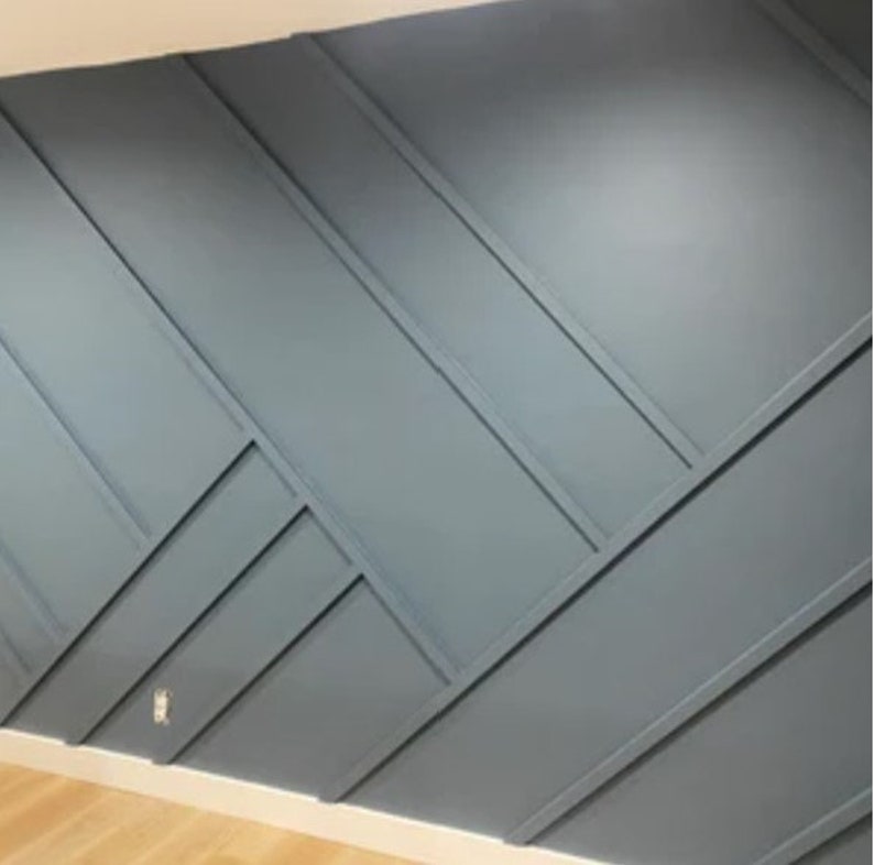 Op de afbeelding: Een muur met een geometrisch patroon gemaakt van geschilderde houten panelen. De panelen zijn in een diagonaal patroon gerangschikt en in een lichtblauwe kleur geverfd.
