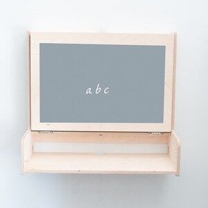 May include: A light wood shelf with a hinged chalkboard panel that says "abc".