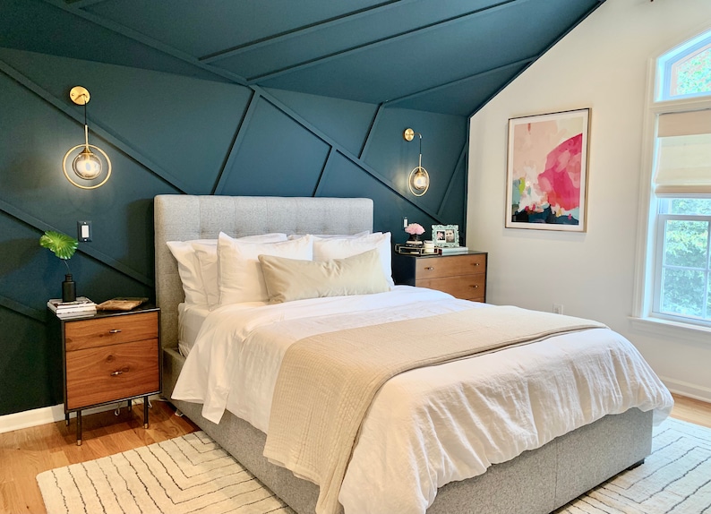 Pode incluir: Quarto com cama estofada cinza, roupa de cama branca e manta bege. As paredes s&atilde;o verde-azulado escuro com pain&eacute;is geom&eacute;tricos. Arandelas douradas com luzes globais. Mesa de cabeceira e c&oacute;moda de madeira vis&iacute;veis.