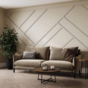 May include: A brown sofa with two throw pillows sits in front of a wall with a geometric pattern. A small round wooden coffee table with a black metal frame sits in front of the sofa. Two white ceramic mugs are on the table. A small side table with a wooden top and black metal legs is to the right of the sofa.