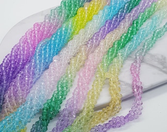 May include: A collection of iridescent glass beads in various pastel colors, including pink, blue, green, and purple. The beads are faceted and have a sparkly finish.