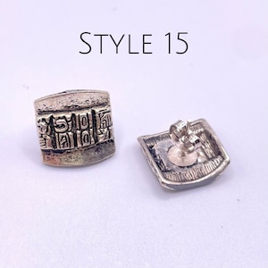May include: A pair of silver earrings with a square shape and intricate designs. The earrings have a post back closure. STYLE 15