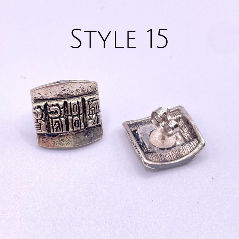 May include: A pair of silver earrings with a square shape and intricate designs. The earrings have a post back closure. STYLE 15