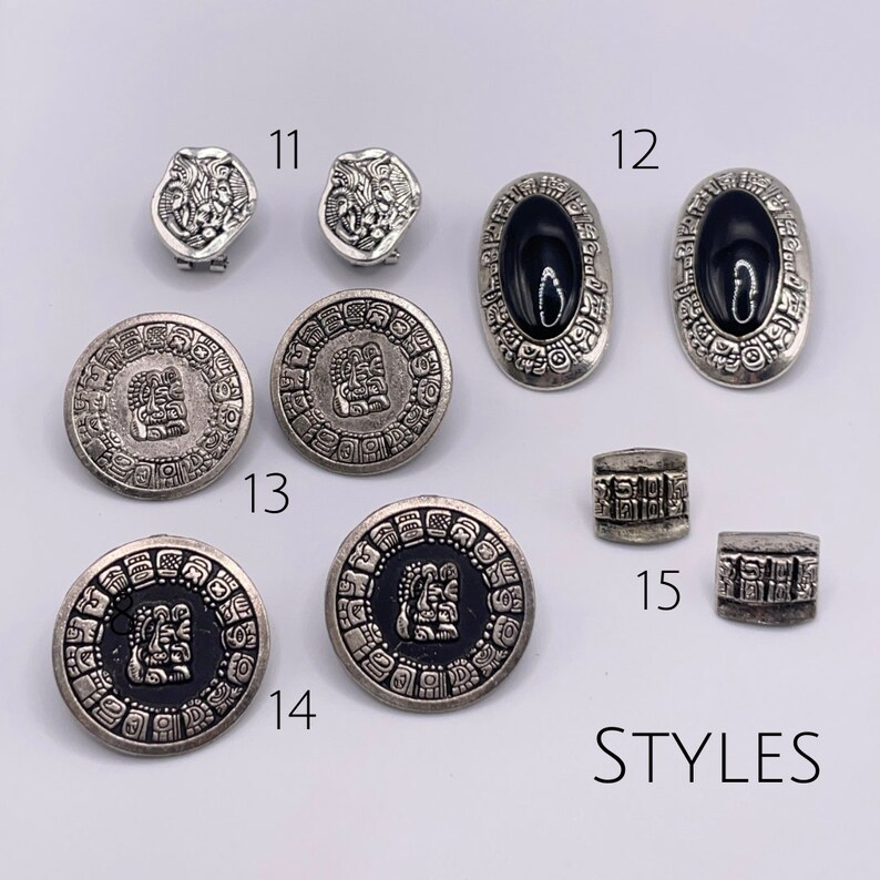 May include: Assortment of silver tone earrings and charms with Aztec inspired designs. The earrings feature black onyx stones and the charms have intricate details. The charms are numbered 11, 12, 13, 14, and 15. The text "STYLES" is written below the charms.