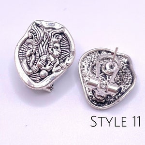 May include: Silver tone clip-on earrings with a detailed design of three figures. The back of the earrings feature a secure clip closure. STYLE 11.