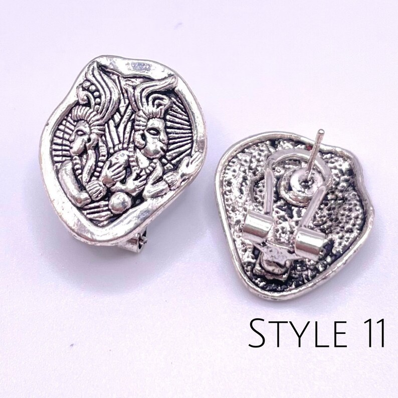 May include: Silver tone clip-on earrings with a detailed design of three figures. The back of the earrings feature a secure clip closure. STYLE 11.