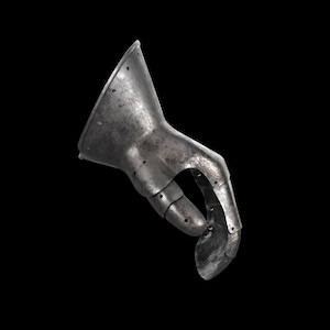 May include: A metallic gauntlet piece featuring a flared cuff and articulated finger segments. The surface displays a weathered, dark grey finish with visible rivets along the joints and edges, showing a segmented construction for hand protection.