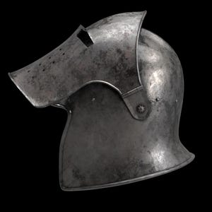 May include: A close-up of a medieval steel helmet with a visor. The helmet is a dark, metallic gray with visible wear and tear, suggesting age. The visor has small holes and a rectangular opening. The helmet is set against a black background.