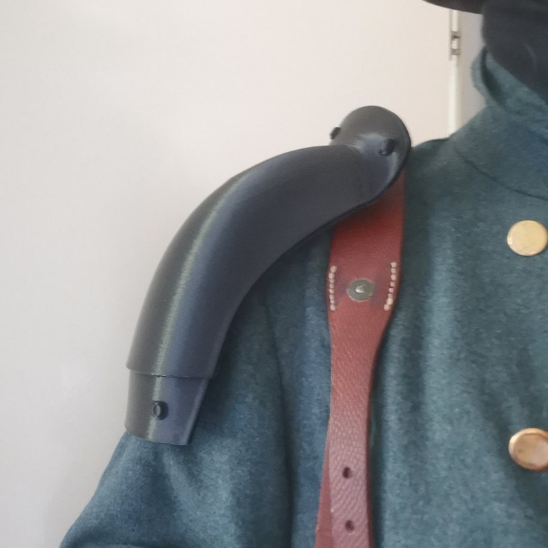 以下が含まれることがあります： 軍服用の黒いプラスチック製の肩パッド。パッドは肩にフィットするように湾曲しており、ストラップの取り付けポイントがあります。