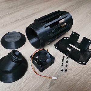 May include: A 3D printed black fan kit with a cylindrical fan housing, a fan, a base, a nozzle, and a mounting bracket. The kit also includes screws for assembly.