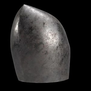 K&ouml;nnte beinhalten: Ein metallischer, kugel&auml;hnlicher Gegenstand mit einer Spitze. Die Oberfl&auml;che hat ein verwittertes, strukturiertes Aussehen mit Farbvariationen, die von Dunkelgrau bis Silber reichen. Der Gegenstand ist vor schwarzem Hintergrund.