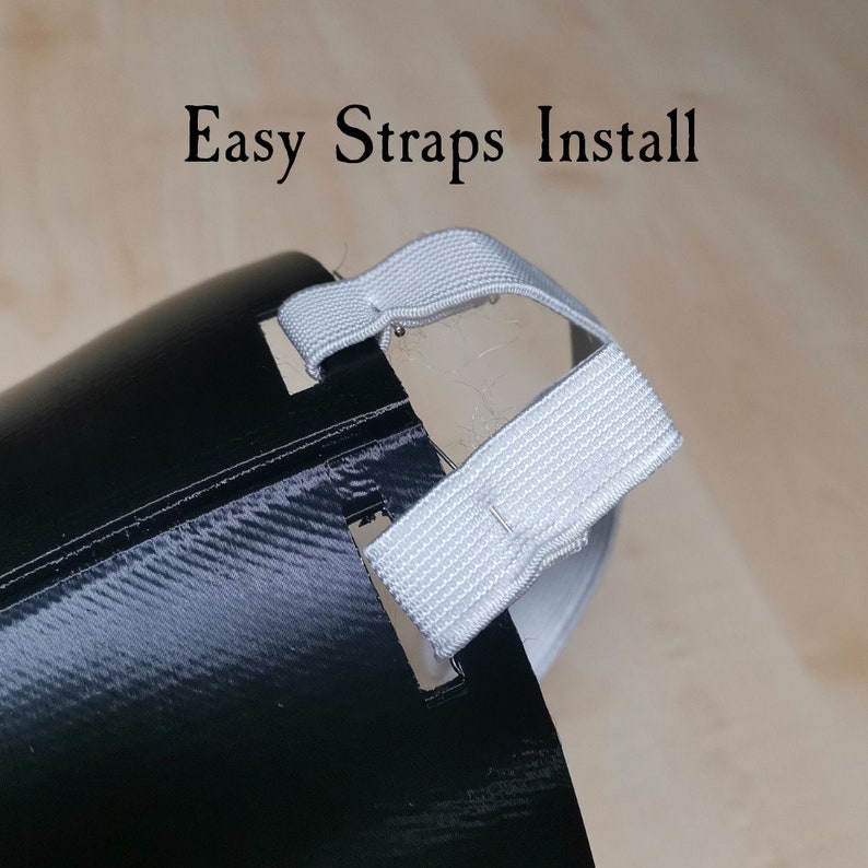 May include: Close-up of a black face mask with white elastic straps. The straps are threaded through holes on the mask and are ready to be tied around the head. The text "Easy Straps Install" is visible at the top of the image.