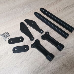 Puede incluir: Un conjunto de piezas impresas en 3D de color negro para una motocicleta, que incluye dos varillas largas, dos soportes curvos, dos placas planas y un peque&ntilde;o juego de tornillos.