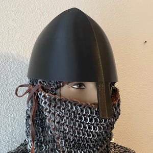 May include: A black medieval helmet with a pointed top, paired with chainmail armor. The helmet has a smooth, matte finish. The chainmail covers the neck and lower face, secured with leather ties.