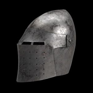 May include: A weathered, steel-colored medieval helmet with a rounded top and a face guard. The helmet features a horizontal eye slit and a series of small ventilation holes. A hinge is visible on the side. The background is black.
