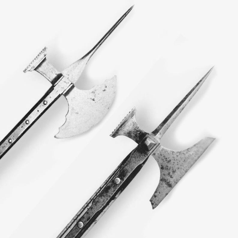 Op de afbeelding: Twee antieke stangwapens met bijlbladen en lange punten. De metalen wapens hebben geklonken schachten en staan tegen een witte achtergrond. De bijlbladen hebben een gebogen vorm en zijn lichtelijk verroest.