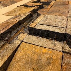 May include: A detailed model of a trench system, featuring a network of trenches and walkways. The trenches are made of wood and have a realistic, weathered appearance. The model is perfect for wargaming or historical dioramas.