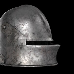 May include: A weathered, steel-colored medieval helmet with a rounded top and a visor. The helmet shows signs of age with visible scratches and discoloration, suggesting historical use. The visor has a horizontal opening for the eyes.