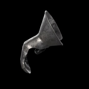 May include: A metallic gauntlet piece featuring a wide, flared cuff and a curved, articulated finger section. The surface has a weathered, dark grey finish with visible rivets along the edges, showing a historical design for hand protection.