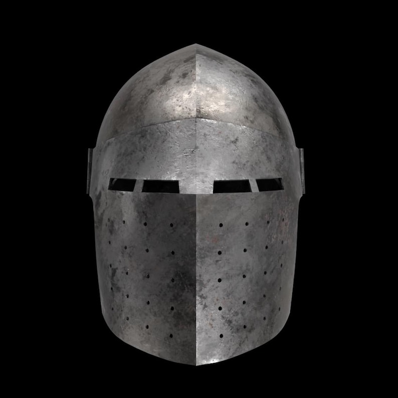May include: A medieval steel helmet with a rounded top and a pointed front. The helmet has a series of small holes and rectangular eye slits. The metal has a weathered, aged appearance against a black background.