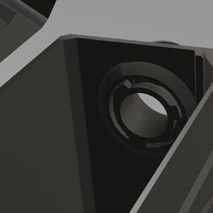 May include: A close-up of a black plastic part with a circular hole in the center. The hole is surrounded by a raised lip.