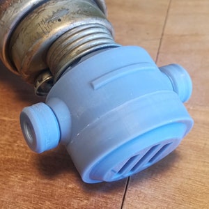 May include: A light blue plastic bottle cap with a small vent on the side. The cap has a round shape with a raised lip around the edge.