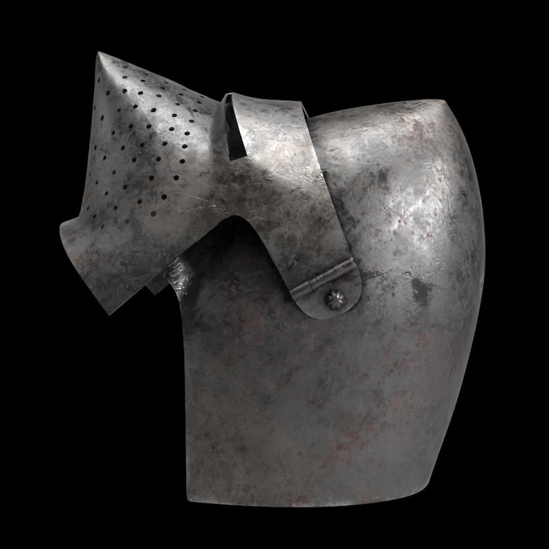 Pode incluir: Uma se&ccedil;&atilde;o de armadura de metal antiga, provavelmente um componente de capacete, contra um fundo preto. A pe&ccedil;a tem uma forma curva com uma viseira perfurada e uma al&ccedil;a. O metal tem uma apar&ecirc;ncia desgastada e envelhecida.