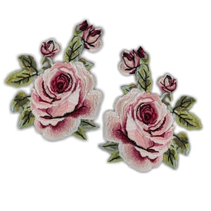 May include: Two embroidered rose patches. Each patch features a large pink rose with a deep red center, surrounded by smaller buds and green leaves. The patches are detailed with various shades of pink and green.