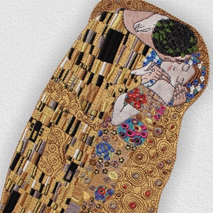 May include: Embroidered artwork depicting Gustav Klimt's The Kiss, featuring two figures in a golden embrace with swirling patterns and colourful details.