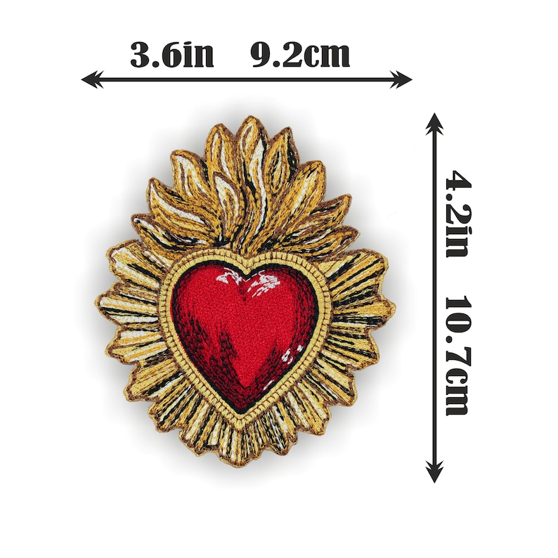 Puede incluir: Un coraz&oacute;n rojo con un dise&ntilde;o de llama dorada a su alrededor. El coraz&oacute;n mide 9,2 cm de ancho y 10,7 cm de alto.