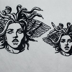 May include: Two black and white Medusa head designs. The larger design features a detailed depiction of Medusa's face with snakes for hair and feathered wings. The smaller design is a similar, but smaller, version of the same image.