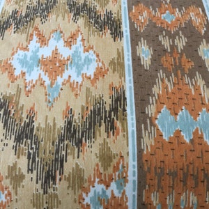 May include: Close-up of a fabric with a repeating geometric pattern. The design features vertical stripes and a mix of colours, including tan, brown, black, and light blue. The pattern has a textured appearance.