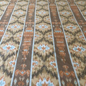 May include: A patterned fabric with vertical stripes in shades of brown, tan, and orange. The design features geometric shapes and a dotted texture. The fabric is likely used for bedding or upholstery.