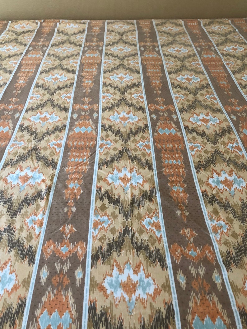 May include: A patterned fabric with vertical stripes in shades of brown, tan, and orange. The design features geometric shapes and a dotted texture. The fabric is likely used for bedding or upholstery.