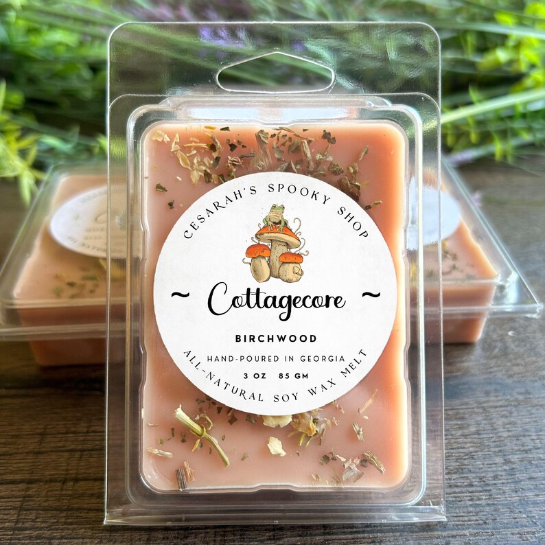 May include: A peach-colored Birchwood soy wax melt in a clear plastic clamshell. The label reads "Cesarah's Spooky Shop" and "Cottagecore" with a mushroom and frog illustration. The melt is 3 oz (85 g) and hand-poured in Georgia.