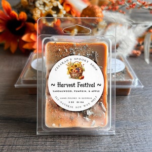 May include: A 3 ounce soy wax melt in a clear plastic container. The wax is a light brown color with a glittery finish. The label reads "CESARAH'S SPOOKY SHOP ~ Harvest Festival ~ SANDALWOOD, PUMPKIN, & APPLE HAND-POURED IN GEORGIA ALL-NATURAL SOY WAX MELT 3 OZ 85 GM".