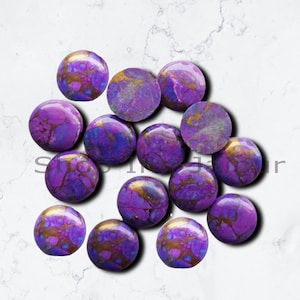 May include: A collection of 15 purple and gold cabochons, each with a unique marbled pattern. The cabochons are round and smooth, and they are perfect for jewelry making.