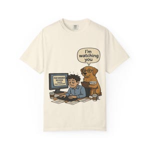 Può includere: T-shirt color crema con un'illustrazione a cartoni animati di una persona al computer, osservata da un cane con gli occhiali e un'etichetta "Manager". Lo schermo del computer mostra "PERFORMANCE REVIEW: needs improvement". Un fumetto dice "I'm watching you."