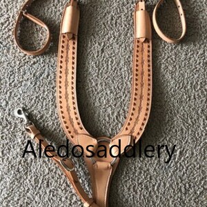 May include: A tan leather horse breast collar with intricate stitching and a silver buckle. The breast collar is designed for use with a saddle and is a popular choice for western riding.